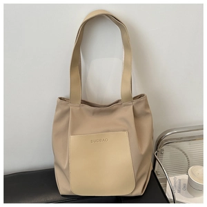 Close-up of beige tote bag with light khaki leather pocket and embossed brand logo