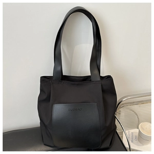Close-up detail of a black nylon tote bag with leather pocket and shoulder strap
