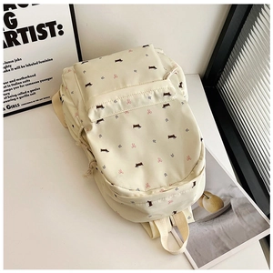 Vue détaillée d'un sac à dos crème avec des motifs mignons de chiots et de nœuds