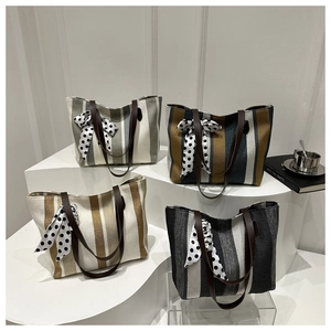Macro shot of striped tote bags with leather handles and decorative bows in diverse colors