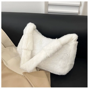 Close-up of white plush crescent shoulder bag on black leather sofa with trench coat