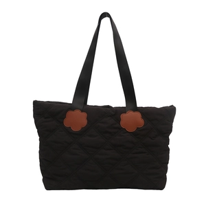 Black quilted large capacity tote bag with brown floral accents and wide shoulder strap