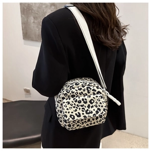 Detailed shot of leopard print crossbody bag with wide shoulder strap on black blazer