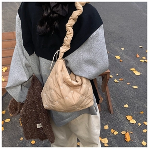 Close-up of beige quilted tote bag with bow embroidery and ruffled shoulder strap detail