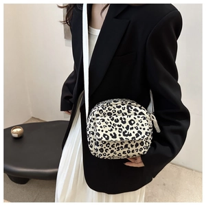 Detail of leopard print canvas crossbody bag with front zipper pocket on model outfit