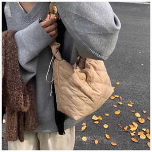 Close-up of quilted khaki tote bag featuring white bow embroidery and ruffled shoulder strap