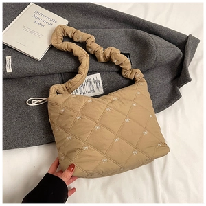 Detailed macro view of khaki quilted tote bag with embroidered bows and ruffled strap