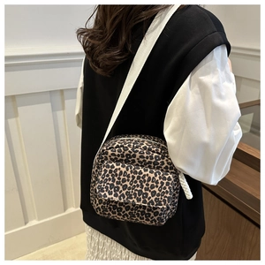 Detail of trendy leopard print crossbody bag with wide woven strap on female model