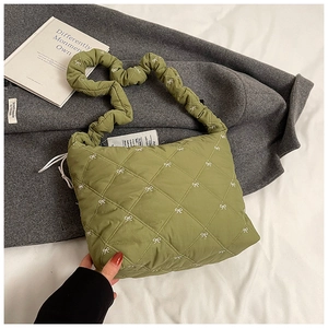 Detail of avocado green quilted bag with bow embroidery and ruched shoulder strap