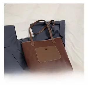 Dettaglio borsa shopper marrone testurizzata con tasca a contrasto su sfondo casual