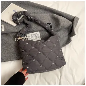 Detailed view of quilted dark grey tote with embroidered bows and soft fabric texture