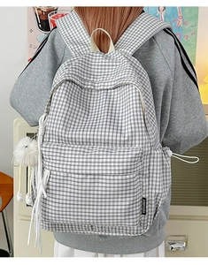 Nahaufnahme des schwarz-weißen Karorucksacks mit Seitenlabel und weißem Plüschkugel-Anhänger