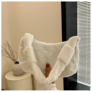Detail showing plush white faux fur texture on a soft hobo shoulder bag held by hand