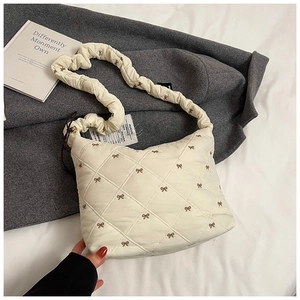 Detail of cream quilted tote bag with embroidered bows and cloud-like ruched shoulder strap