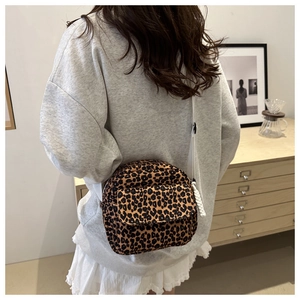 Detail of leopard print crossbody bag with adjustable white strap on a lifestyle model