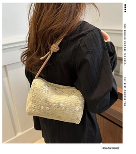 Detailed close-up of straw woven cylinder bag with delicate floral embroidery and leather strap