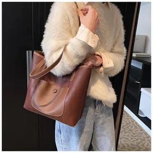 Dettaglio di una borsa tote in pelle marrone con cuciture a contrasto e tasca anteriore