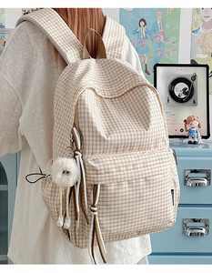 Detailansicht eines beigen karierten Rucksacks mit Plüschtier und Seildekoration