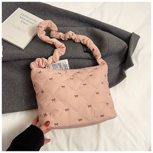Close-up of pink quilted tote featuring bow embroidery and ruffled shoulder strap
