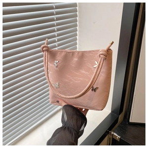Détail d'un sac cabas plissé rose avec breloques papillon argentées et anse nouée