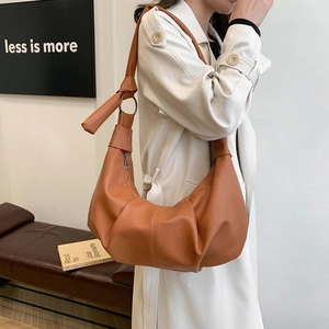 Close-up of caramel crescent bag featuring lychee texture and knotted shoulder strap detail