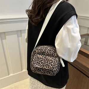 Chic leopard print crossbody bag with a wide white shoulder strap worn by a model