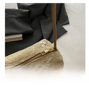 Close-up of golden zipper and pink floral embroidery on a beige woven cylinder bag