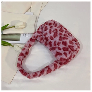 Close-up of soft faux fur shoulder bag with pink and red heart pattern and plush texture