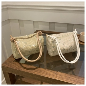 Detail of hand-woven pillow bags with floral embroidery and elegant knotted handles