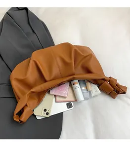 Macro view of large brown pleated leather bag showing spacious interior with personal items