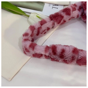 Detailed macro view of pink plush faux fur bag strap with red heart pattern and soft texture