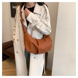 Detail of caramel brown pleated leather bag showing textured finish and knotted strap design