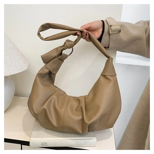Detail of khaki hobo bag featuring lychee grain leather, knot strap, and metal ring accents