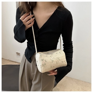 Detailed shot of cream straw pillow bag with delicate floral embroidery and thin leather strap