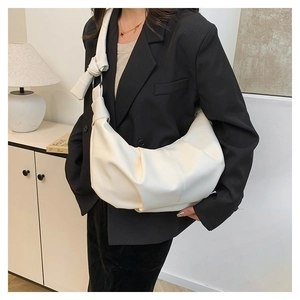 Detail view of white pleated dumpling bag with soft lychee grain texture and knot detail