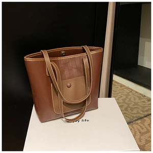Dettaglio di una borsa tote marrone con trama in pelle intrecciata e chiusura magnetica