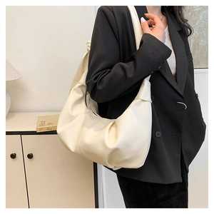 Close-up of cream pleated hobo bag with litchi texture on a model in a black blazer