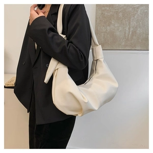 Detail of creamy off-white leather shoulder bag with stylish knot strap and pleated design