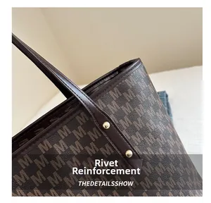 Detail showing the heavy-duty metal rivet reinforcement and monogram pattern on tote bag