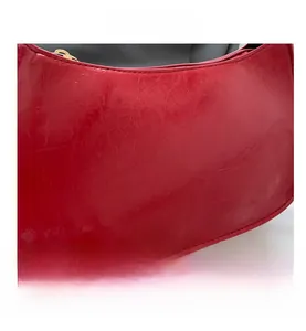 Detailed macro view showing the glossy embossed red leather texture of the crescent bag