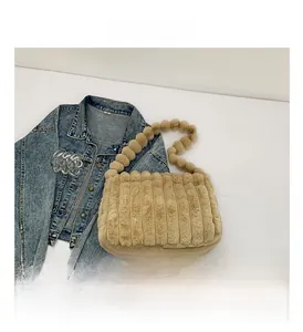 Detail of plush khaki tote bag featuring striped texture and unique fuzzy ball strap