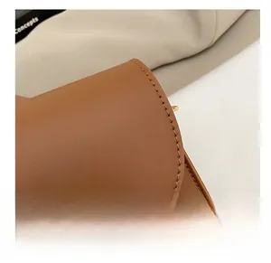 Détail des coutures précises et des ferrures dorées sur un sac à bandoulière en cuir brun