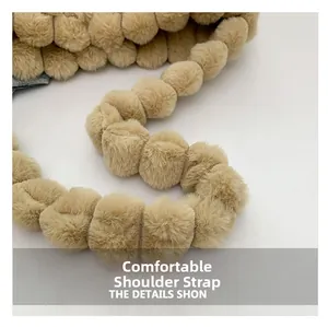 Detail showing soft plush ball shoulder strap of the khaki faux fur tote bag