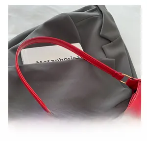 Detail of red patent leather crescent bag with golden metal zipper and glossy finish