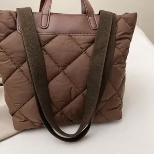 Detail showing brown quilted down texture fabric and wide woven shoulder strap on the tote
