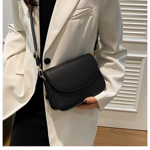 Détail d'un sac à bandoulière noir minimaliste avec sangle réglable et gravure de mode