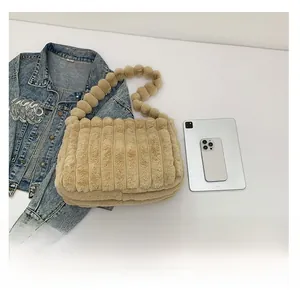 Close-up of beige fuzzy tote bag featuring a unique fluffy ball beaded shoulder strap