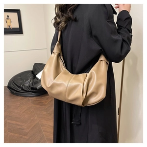 Detail of khaki pleated dumpling bag with lychee texture leather on a model outfit
