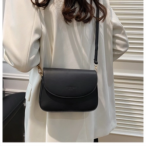 Détails du sac à bandoulière noir minimaliste avec ferrures dorées sur modèle
