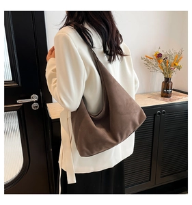 Modella che indossa una grande borsa hobo in pelle scamosciata marrone in interni
